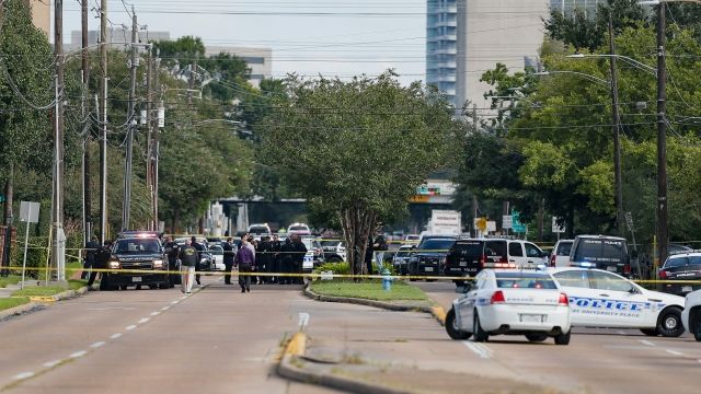 Multiple police vehicles and officers at the site of a shooting near a Houston shopping center.
