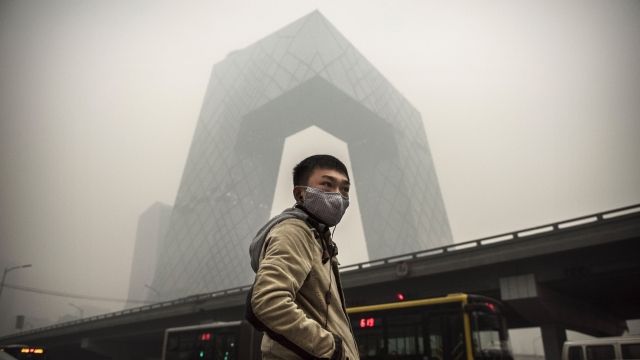 A Chinese man wears a mask as he waits to cross the road near the CCTV building during heavy smog in Beijing.