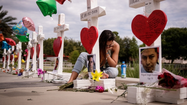 A woman writes a note on a cross at a memorial with wooden crosses for each of the victims of the Pulse nightclub shooting.
