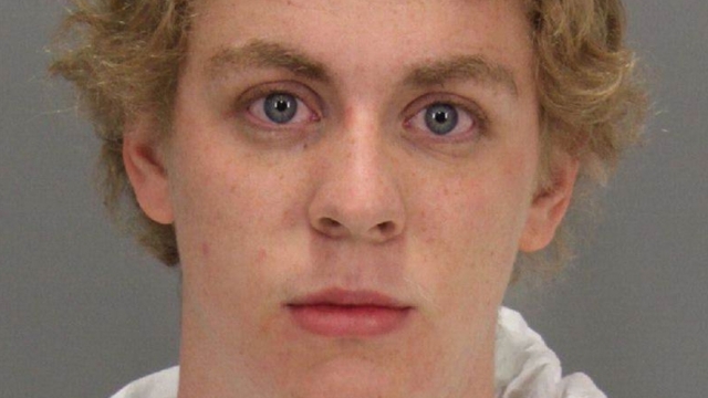Brock Turner wears a hooded sweatshirt and stares into the camera in this mugshot. He has curly hair.