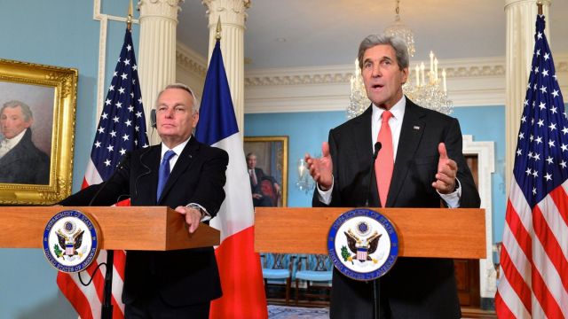 French Foreign Minister Jean-Marc Ayrault and Secretary of State John Kerry stand at podiums.
