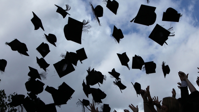 Students throw their mortarboards in the air during their graduation photograph.