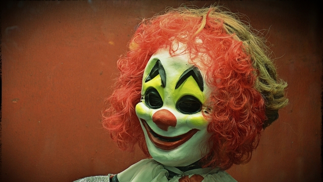 A person wears a clown mask.