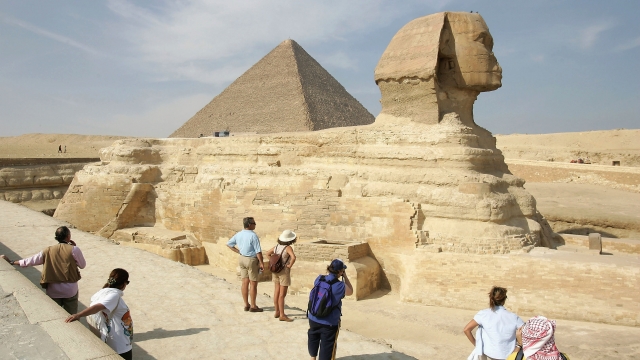 Tourists marvel at the Sphinx while Khufu pyramid looms behind November 13, 2004 at Giza, just outside Cairo, Egypt.