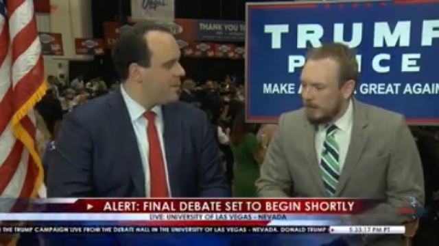 Two men wearing suits with ties sit in front of a large "Trump Pence" sign. This is a screengrab of the Facebook Live video.