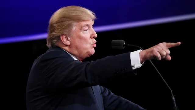 Donald Trump points a finger with his arm out in front of him while speaking at a debate
