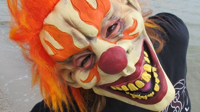 A person in a creepy clown mask stares into the camera.