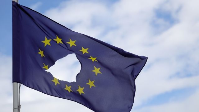 A European Union flag waves with a hole.