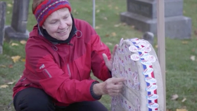 A woman puts an "I voted" sticker on Susan B. Anthony's grave.