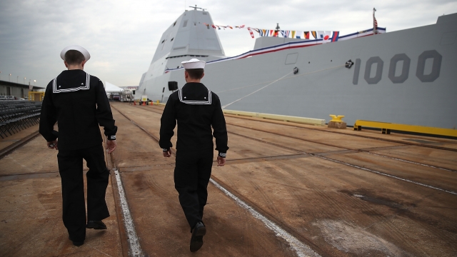 Sailors walk past USS Zumwalt