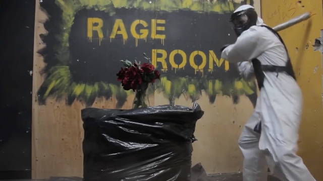 A person smashes items in a rage room in Toronto