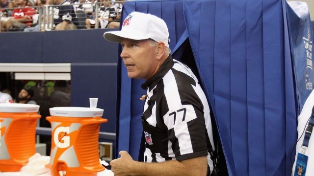 An NFL referee walks out of a replay booth.