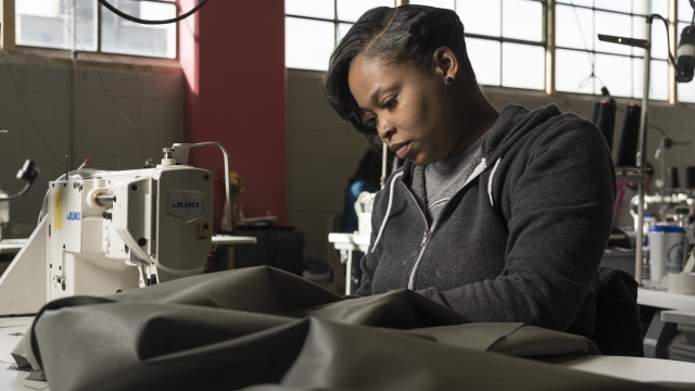 An employee at The Empowerment Plan sews a coat