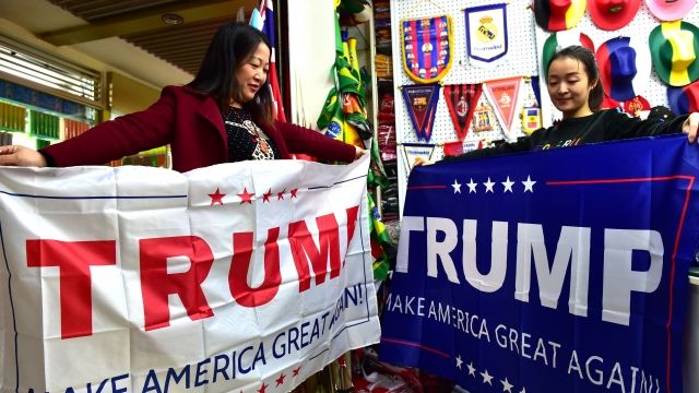 Two women in China hold Trump campaign banners.