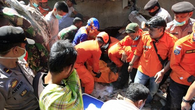 Rescue workers pull victims from building destroyed by earthquake