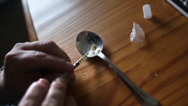 A heroin user prepares to inject himself.