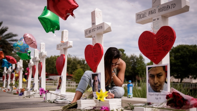 A woman writes a note on a cross for Eric Ivan Ortiz-Rivera at a memorial.