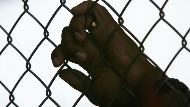 Inmate's hand holding on to a fence.