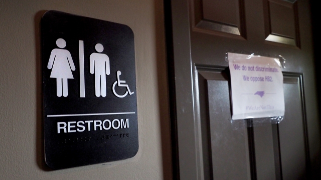 A unisex sign and a nondiscrimination slogan outside a bathroom