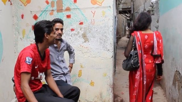 A transgender woman walks by men in Pakistan