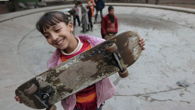 Afghan girl holding skateboard