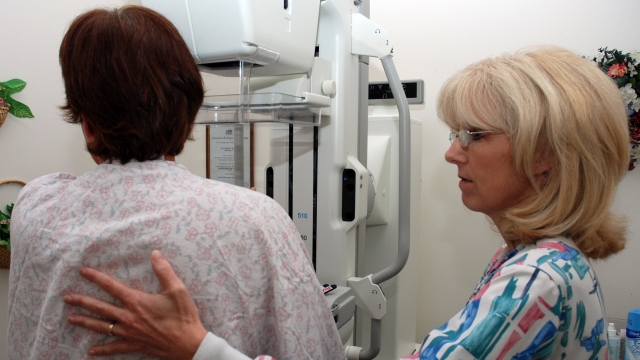 A mammography technologist assists a patient preparing for a mammography.