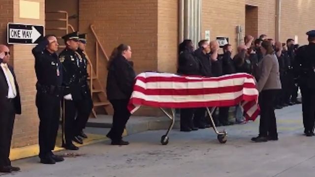 Master Sgt. Debra Clayton's coffin is draped with a flag and transported out of the medical examiner's office.