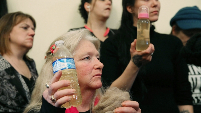 Flint residents hold bottles full of contaminated water.