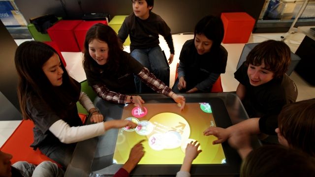 Children trying touch-screen digital learning table
