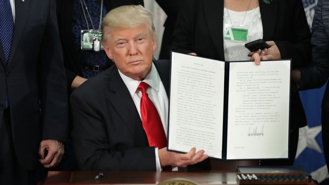 President Donald Trump displays an executive order he signed.