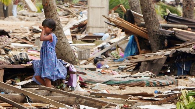 A girl stands on rubble after a tsunami in Sri Lanka