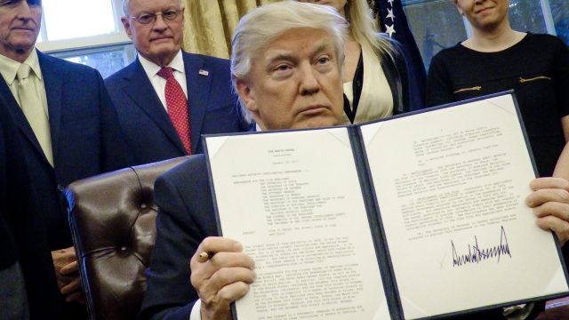 President Donald Trump holds a signed executive order