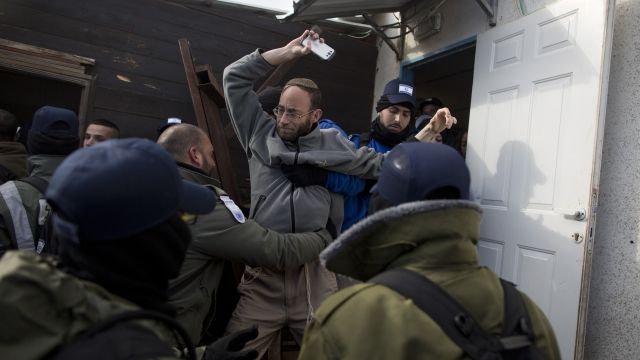 Israeli police force a man to move from a settlement