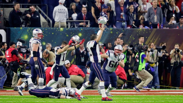 Tom Brady and his teammates celebrate on the field after their Super Bowl win.