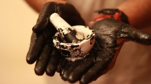 Hands covered in ink made from smog