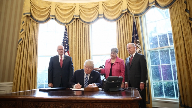 Donald Trump signs an executive order in the Oval Office.