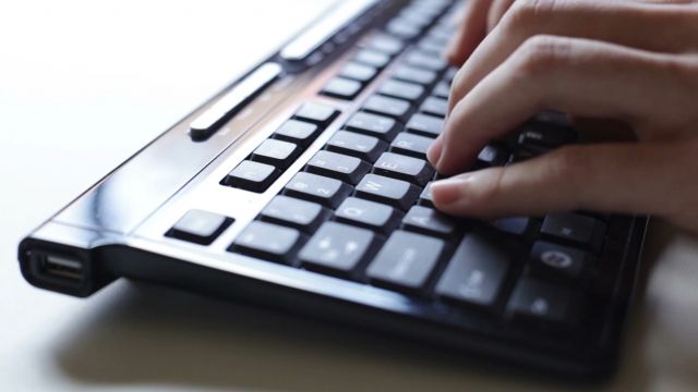 Hands type on a computer keyboard.