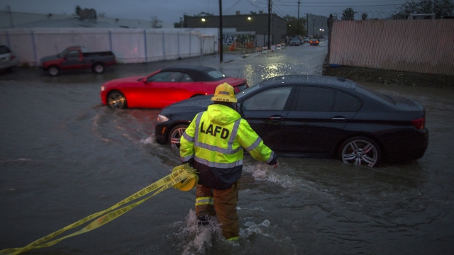 A firefighter carries caution tape in a flooded street.