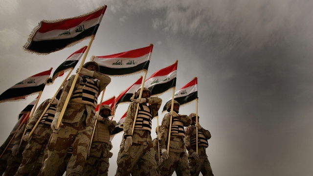 Iraqi army soldiers hold flags.