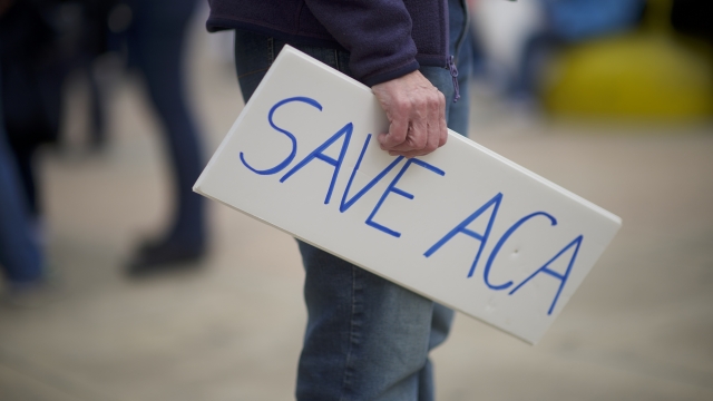 Protester holding a sign that says "Save ACA"