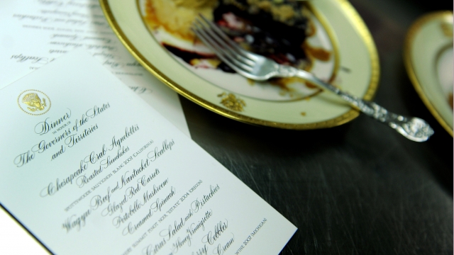 An empty plate sits next to a menu during the Governors' dinner