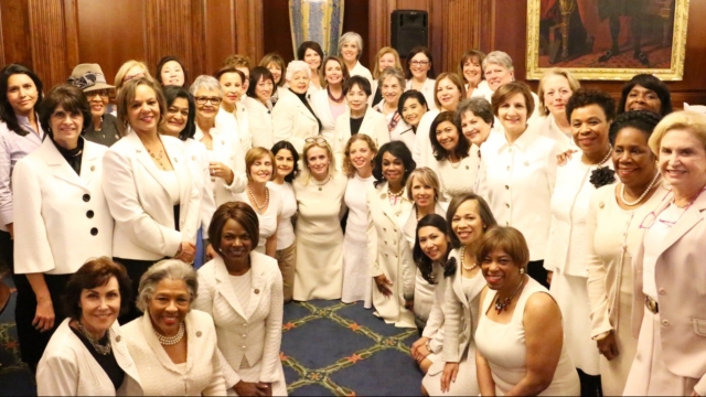 Congresswomen pose wearing white outfits.