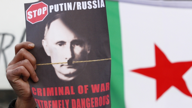 A protester holds a placard showing a portrait of Russian President Vladimir Putin altered to look like Adolph Hitler