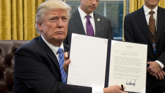President Donald Trump shows an executive order he signed.