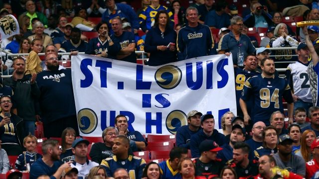 St. Louis Rams fans hold a sign opposing the move to Los Angeles.