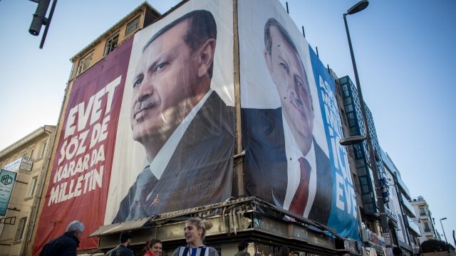 People walk past a "yes" campaign billboard showing the portrait of Turkish President Recep Tayyip Erdogan.
