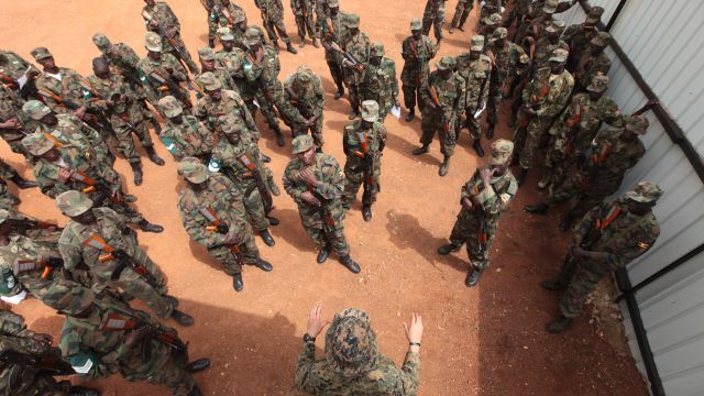 A force reconnaissance Marine goes over threat detection methods with a group of Ugandan soldiers