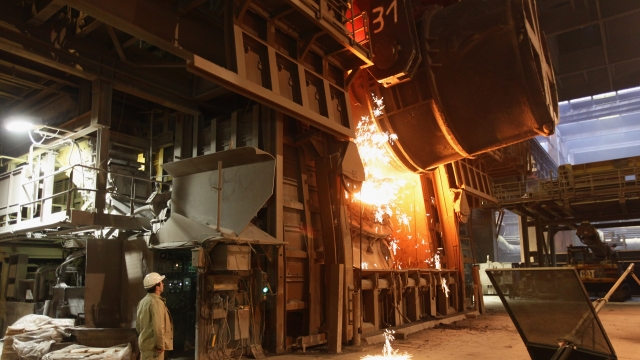 A worker watches as molten iron flows into a furnace for purification and alloying to become steel.