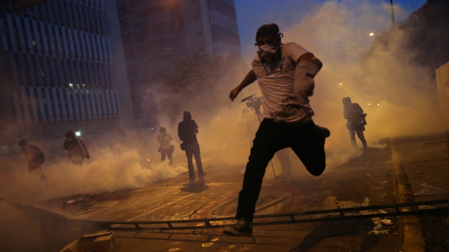 Protesters run from tear gas fired by the Venezuelan national guard.