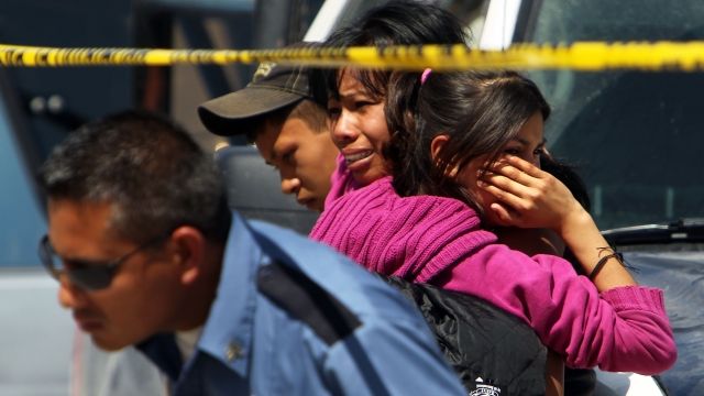Family members cry in front of a car in which two men lay dead in Juarez, Mexico.
